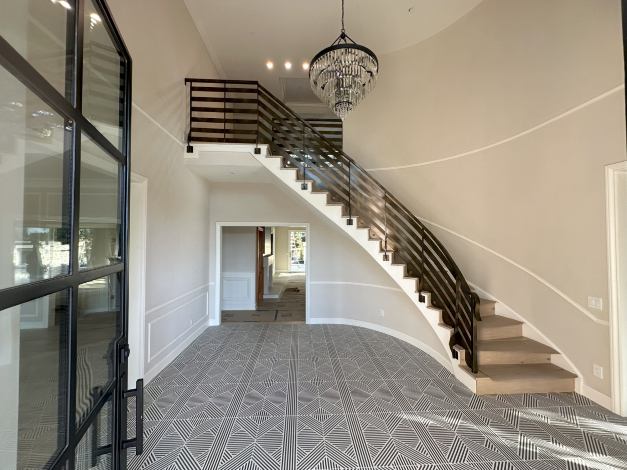 Elegant interior view featuring a curved staircase and a chandelier in a spacious entryway.
