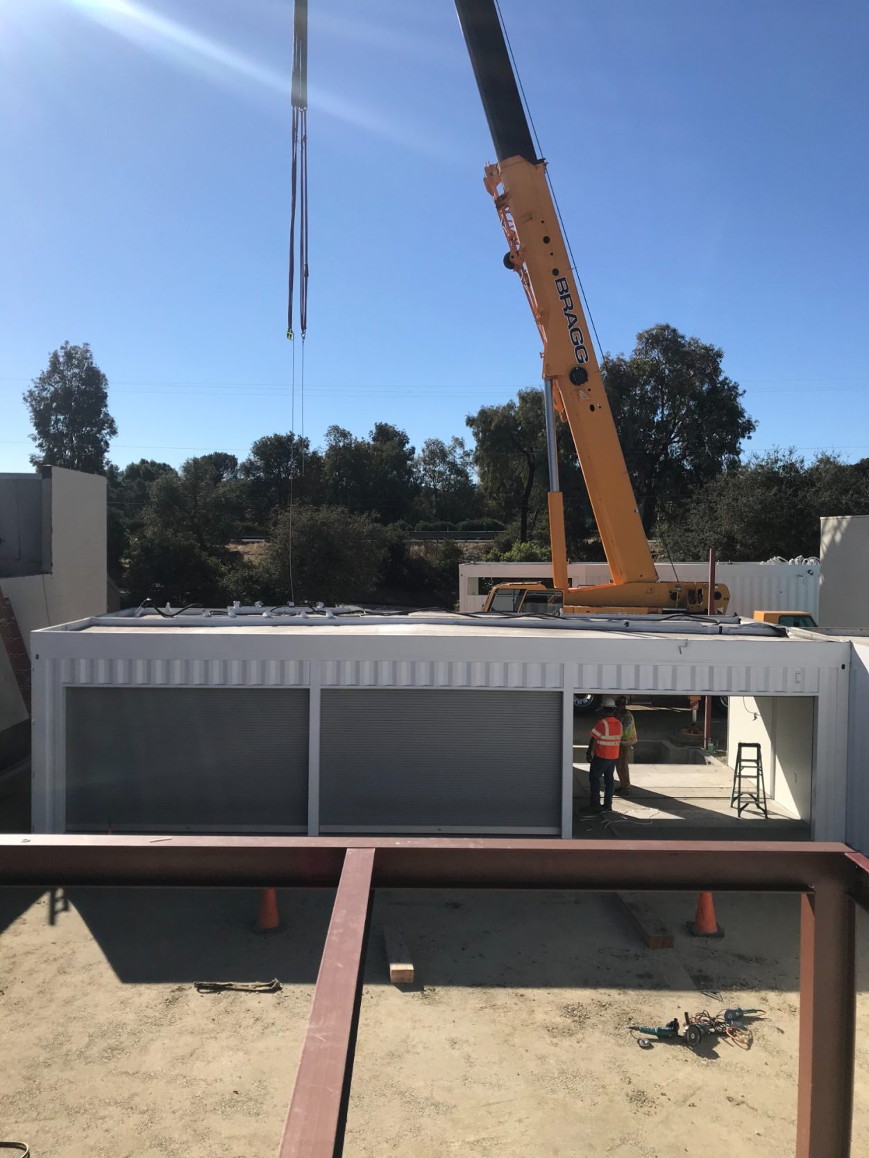 Structural Steel Construction site with a crane lifting materials over a building structure.