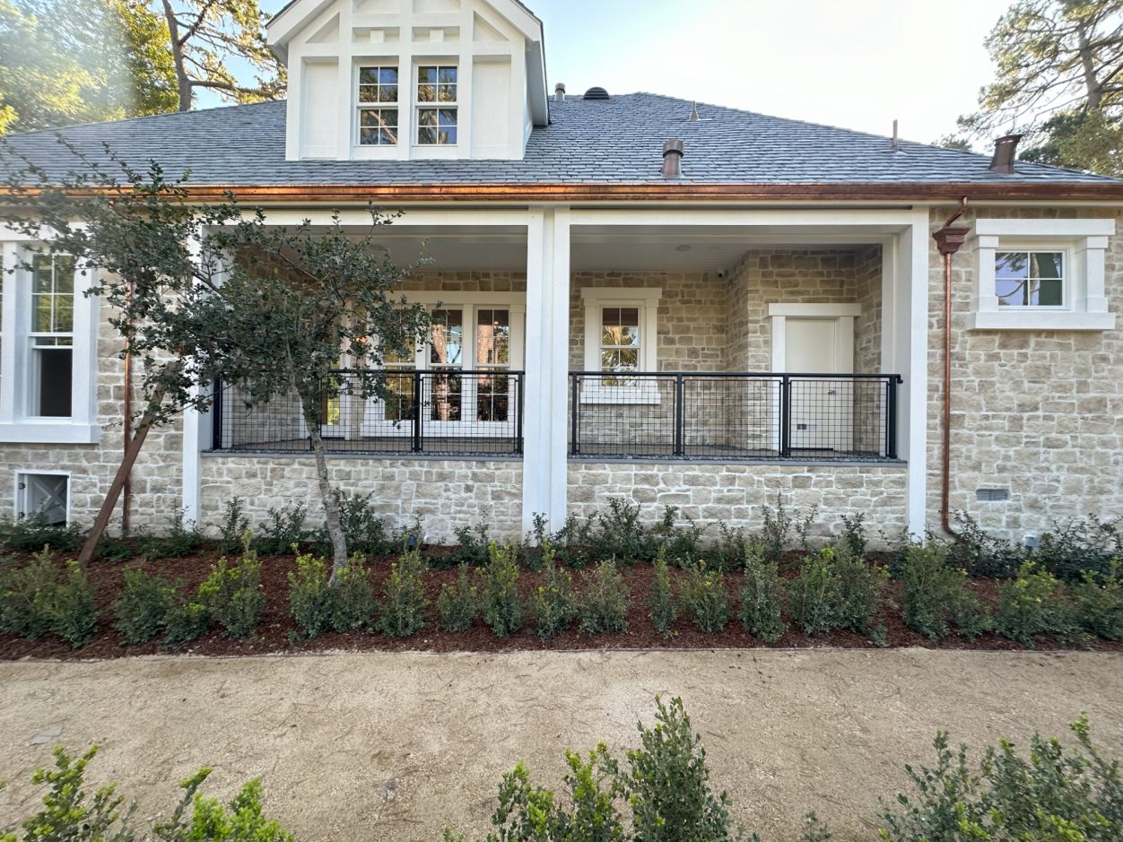 Newly built house with stone façade, porch, and landscaped front yard.