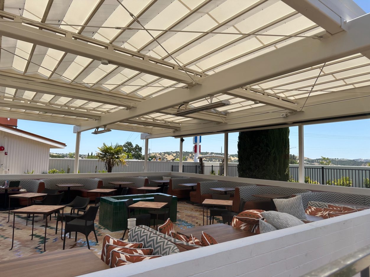 Rooftop seating area with covered patio, tables, and outdoor furniture.